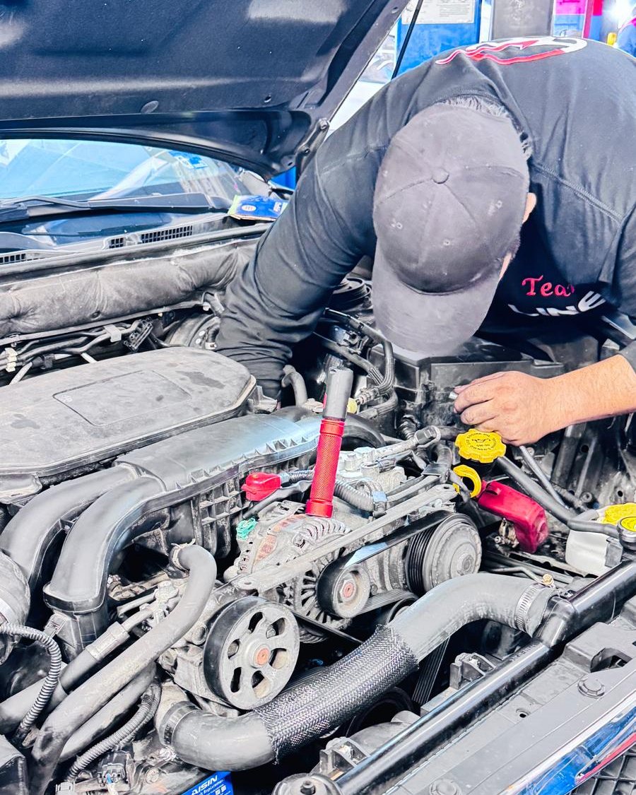 Un técnico de Frontline Auto Plus trabajando en el motor del carro de un cliente